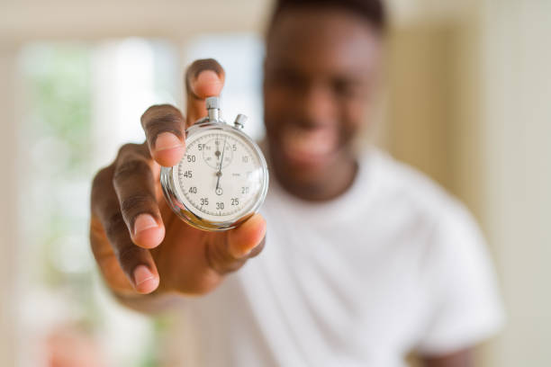 istock Young african man holding silver retro stopwatch counting time 1158253955