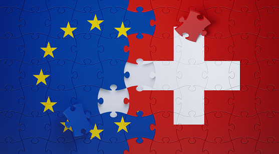Jigsaw puzzle pieces textured with European Union and Swiss flags. Horizontal composition with copy space and selective focus. Solution concept.