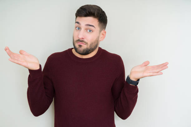 istock Young handsome man wearing a sweater over isolated background clueless and confused expression with arms and hands raised. Doubt concept. 1158256620