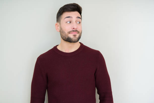 young handsome man wearing a sweater over isolated background smiling looking side and staring away thinking. - mannered imagens e fotografias de stock