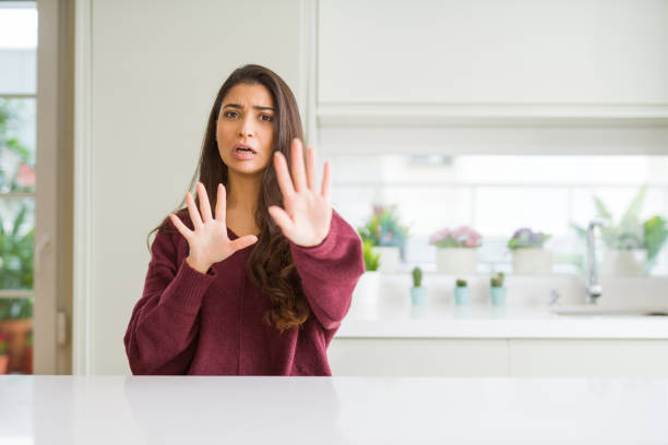 istock Young beautiful woman at home afraid and terrified with fear expression stop gesture with hands, shouting in shock. Panic concept. 1158258438