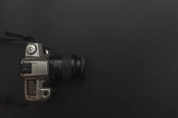 istock Photographer workplace with dslr camera system on dark black table background. Hobby travel photography concept 1158258748