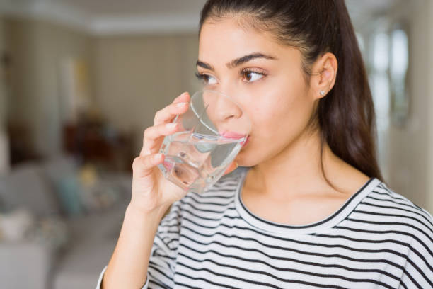 家で水の新鮮なガラスを飲む美しい若い女性 - water women glass healthy eating ストックフォトと画像