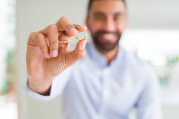 Handsome man smiling and showing wedding alliance ring