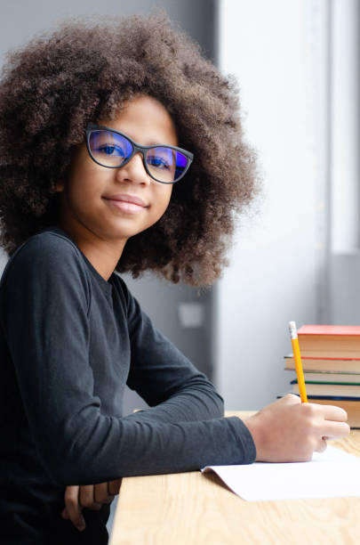 istock Dark-skinned girl sitting at the table teaches lessons. 1158260168