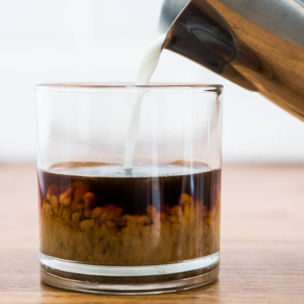 istock Pouring milk over coffee. Side view. 1158262647