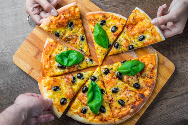 istock hands take a slice of Pizza with Mozzarella cheese, Tomatoes, pepper, olive, Spices and Fresh Basil. Italian pizza. Pizza Margherita or Margarita on wooden table background 1158269061