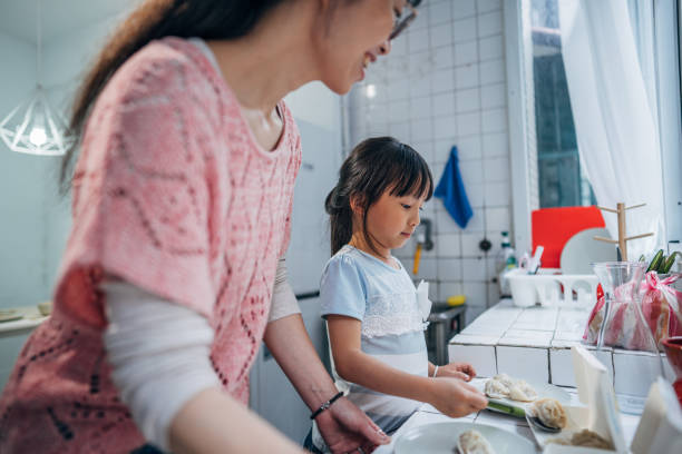 Mother and daughter Taiwanese mother and daughter standing at kitchen and serving dumplings for dinner. girls getting ready to go out stock pictures, royalty-free photos & images