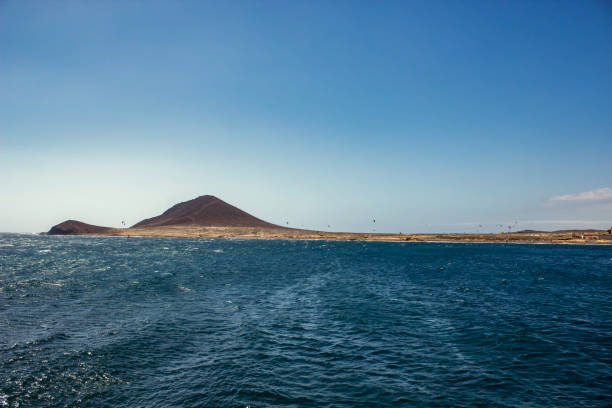 hermosa vista costera de montana roja - montaña roja. brillante cielo azul claro sobre la línea horizonte, ondas ondulaciones en el agua turquesa. el medano, tenerife - montana water landscape nature fotografías e imágenes de stock