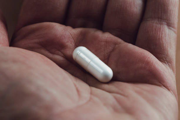 istock close up of a hand holding a white capsule pill 1158270701