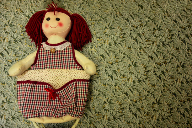 Handmade sew doll with smiling face on floral print background with copy space