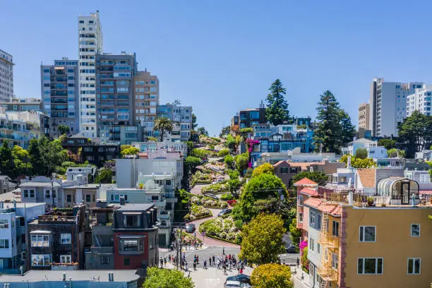 An aerial view of the famous "crooked" street in San Francisco, Lombard Street. A bright sunny day with a clear view. Tourists fill the street where Lombard meets Leavenworth St. in San Francisco.