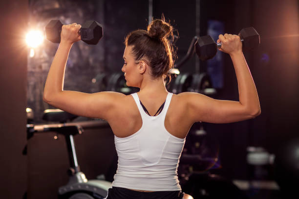 istock Strong young beautiful sexy gril exercise with weights on hands in gym 1158273028