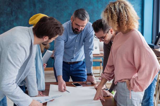 istock Passionate about their project. Group of young business people working together in creative office while standing near the wooden desk. 1158281302