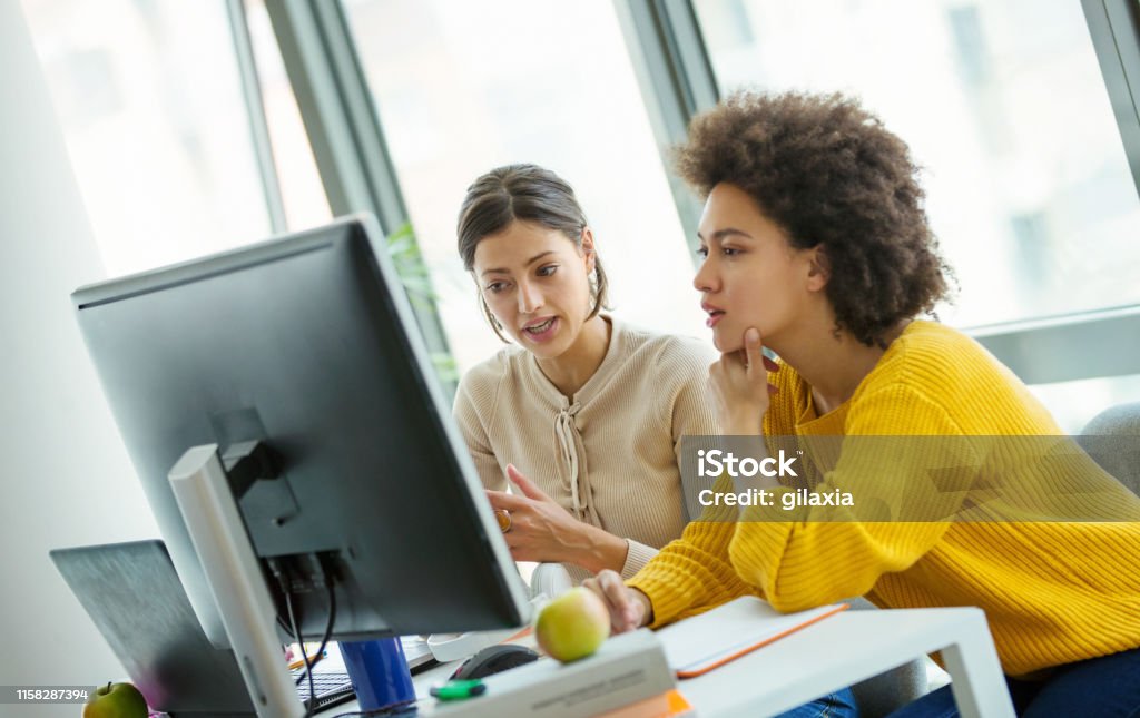 App developers at the office. Closeup side view of a multi ethnic group of mid 20's software engineer working at a small startup office. They are deeply focused while looking at a large computer screen. Office Stock Photo