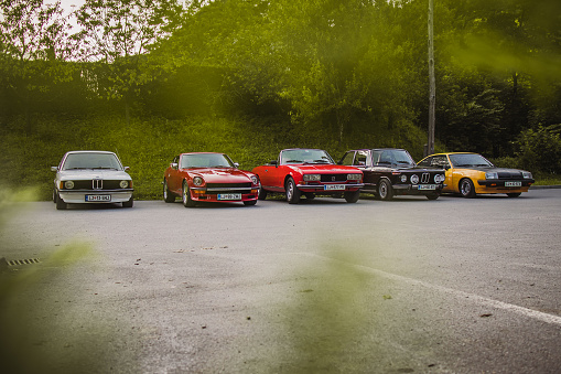 Polhov Gradec, Slovenia, 25.6.2019: A group of old vintage cars, including Datsun 240Z, Opel Manta B, Peugeot 504 and Bmw E21 325 and 2002 tii, waiting to start the ride.