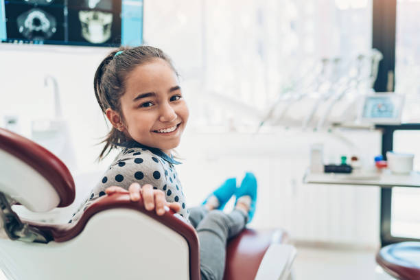 porträt eines lächelnden mädchens, das auf einem zahnarztstuhl sitzt - hygiene dental hygiene human teeth child stock-fotos und bilder
