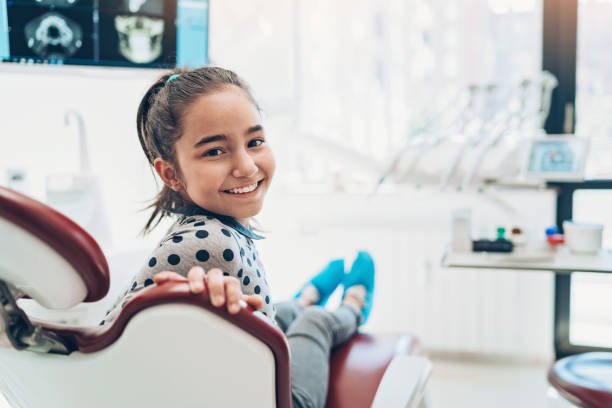 verticale d'une fille de sourire s'asseyant sur la présidence d'un dentiste - dentist teenager dental hygiene sitting photos et images de collection