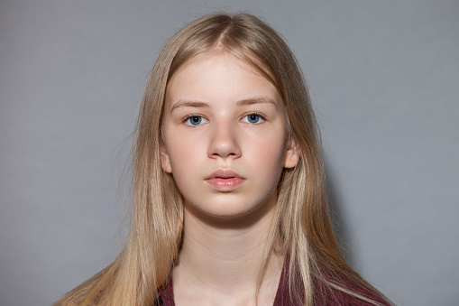 Portrait of beautiful young girl with blondie hair. Confident female wearing blue shirt while posing at grey background. Copy space.