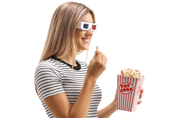 istock Young female eating popcorn and watching with 3D glasses 1158299053