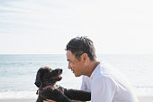 ビーチでリラックスした犬を持つアジアの男