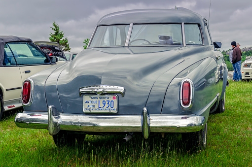 Chester, Nova Scotia, Canada - June 22, 2019 : 1950 Studebaker Champion Starlight Coupe on display at annual Graves Island Car Show at Graves Island Provincial Park, Chester, Nova Scotia Canada. A man walks in the park in front of the Studebaker.