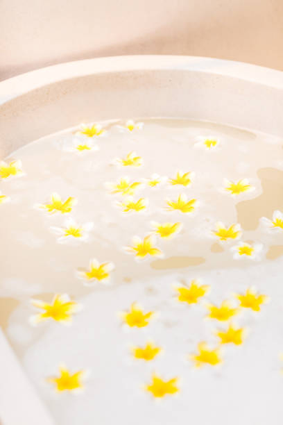 Bathtub with foam bubbles and yellow flowers close-up