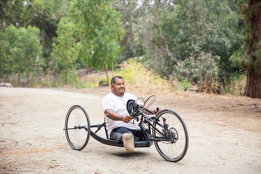 A mature hispanic man rides his handcycle. He is a double amputee.