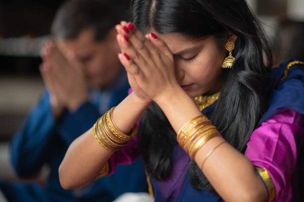 A beautiful Indian family sits in their living room one afternoon praying together. They are celebrating and giving thanks during the holiday Diwali. They are bonding as they are donned in traditional clothing. A beautiful Indian family sits in their living room one afternoon praying together. They are celebrating and giving thanks during the holiday Diwali. They are bonding as they are donned in traditional clothing. religion god stock pictures, royalty-free photos & images