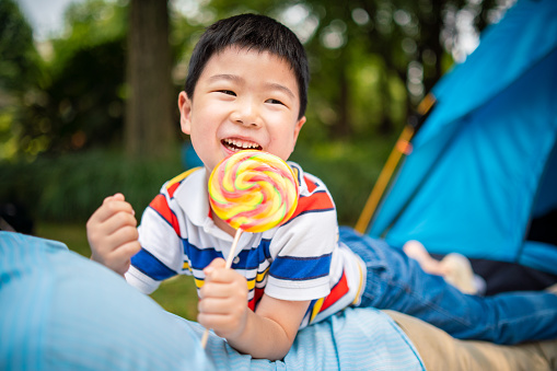 Cheerful Asian boy enjoying a lollipop.