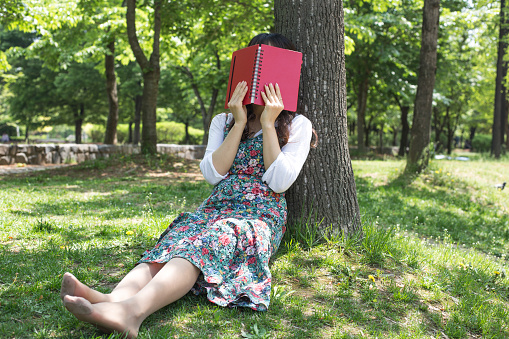 Woman sitting face down on grass with book