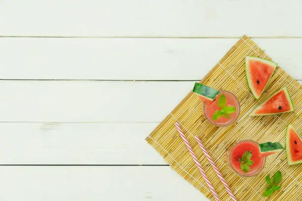 Photo of Table top view fruit tropical with drink with spring summer holiday & vacation background concept.Arrangement slices watermelon with juice on modern white wooden.Copy space for creative design text.