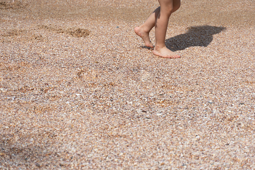 barefoot small leg of young child walking on summer sea beach vacation travel background