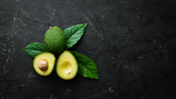 istock Fresh avocado with leaves on a black background. Top view. Free space for your text. 1158331651