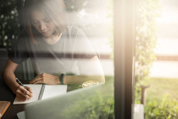 istock Young asia student writting on notebook at coffee shop. 1158343726