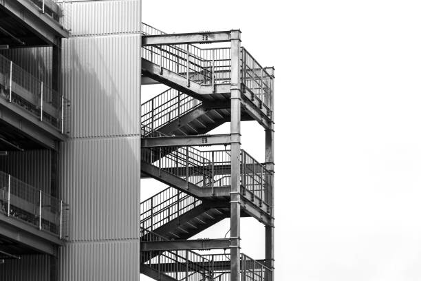 istock empty external metal fire escape stairs construction out side of modern building with copy space. black and white color 1158348347