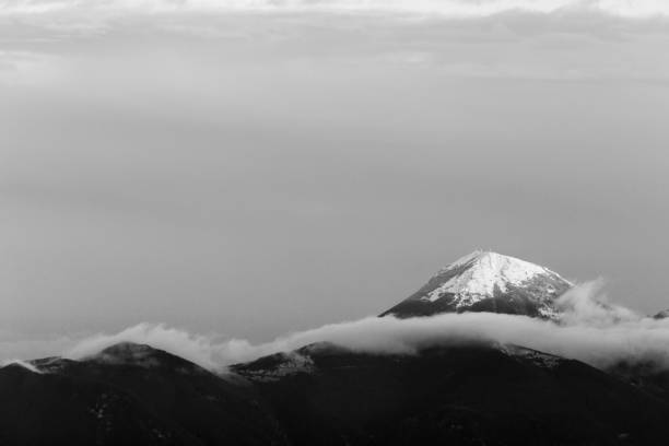 istock Mountain top covered by snow in the middle of clouds 1158352050