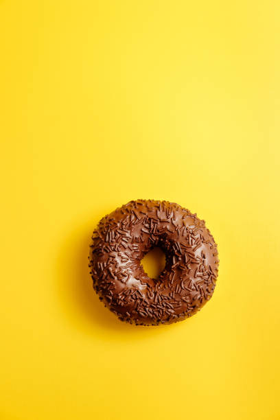istock chocolate donut on yellow background top view 1158352838