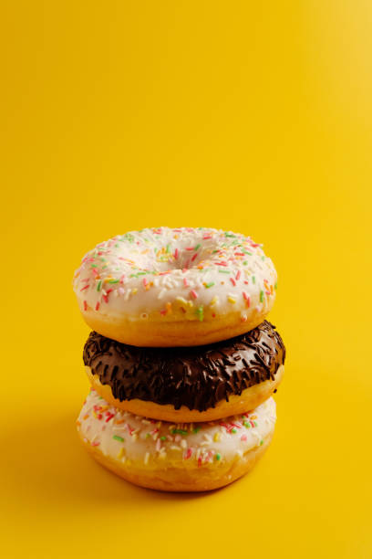 istock three white and black donuts on yellow background copy space 1158353751