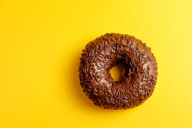 istock chocolate donut on yellow background top view 1158353928