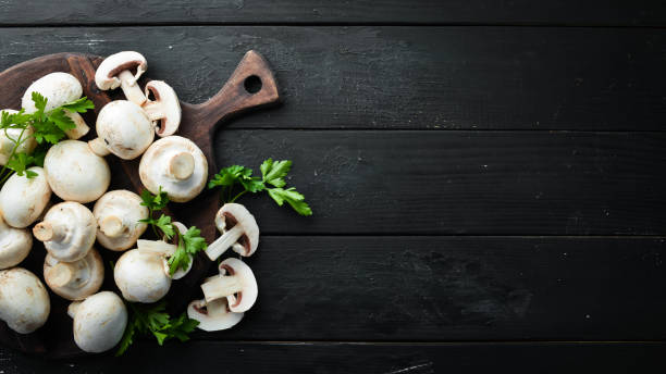 istock Champignons mushrooms on a black wooden table. Top view. Free space for text. 1158354132