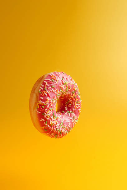 istock pink donut on yellow background 1158354725