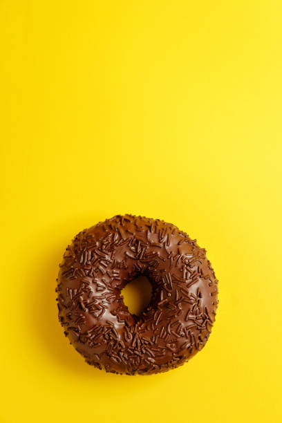 istock chocolate donut on yellow background top view 1158354981