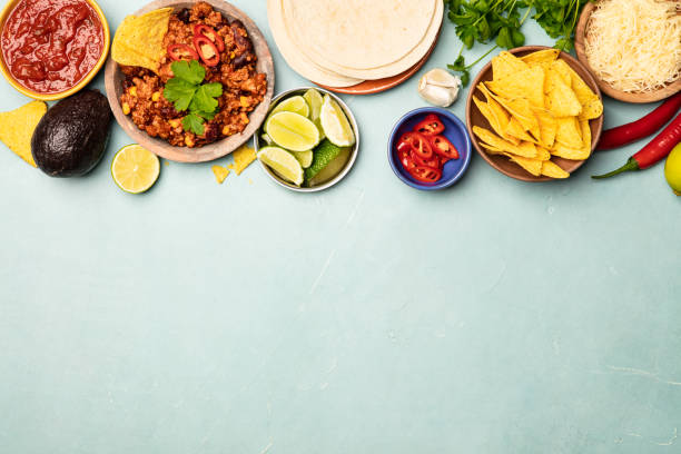 Concept of Mexican food, flat lay Concept of Mexican food (corn tortillas, nachos, salsa, avocado, limes, cheese, chili con carne) flat lay hot mix plant stock pictures, royalty-free photos & images