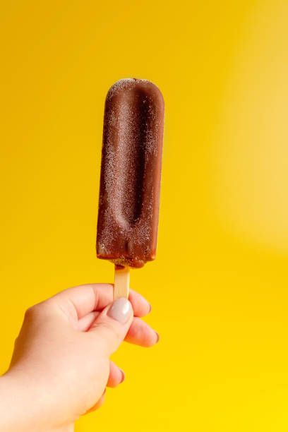 istock chocolate ice cream in hand on yellow background 1158356208