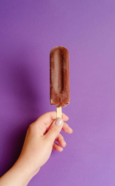 istock chocolate ice cream in hand on purple background 1158356303