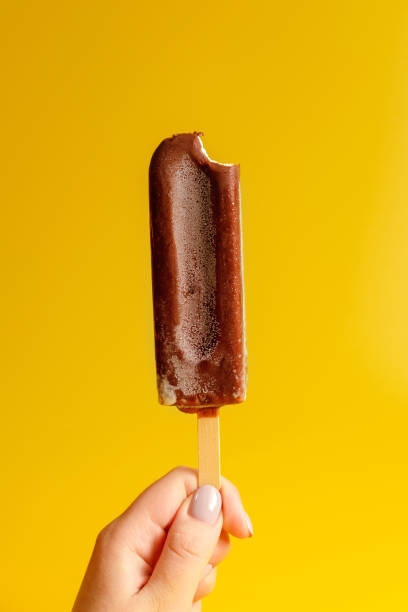 istock chocolate ice cream in hand on yellow background 1158356435