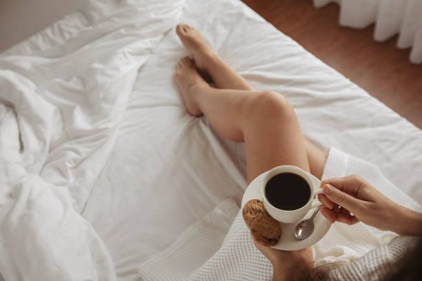 istock Beautiful girl drinks coffee with cookies bed 1158358112