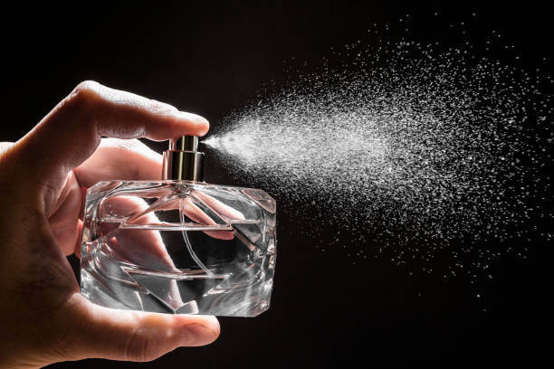 spraying perfume on dark background, closeup  - Image spraying perfume on dark background, closeup  - Image perfume stock pictures, royalty-free photos & images