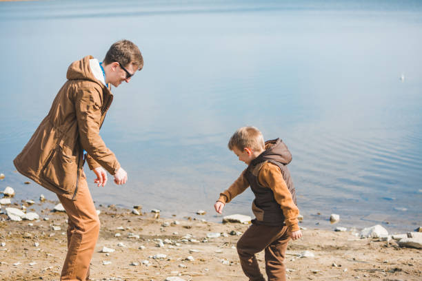 pai que ensina o filho pequeno joga rochas na água - throwing stone little boys child - fotografias e filmes do acervo